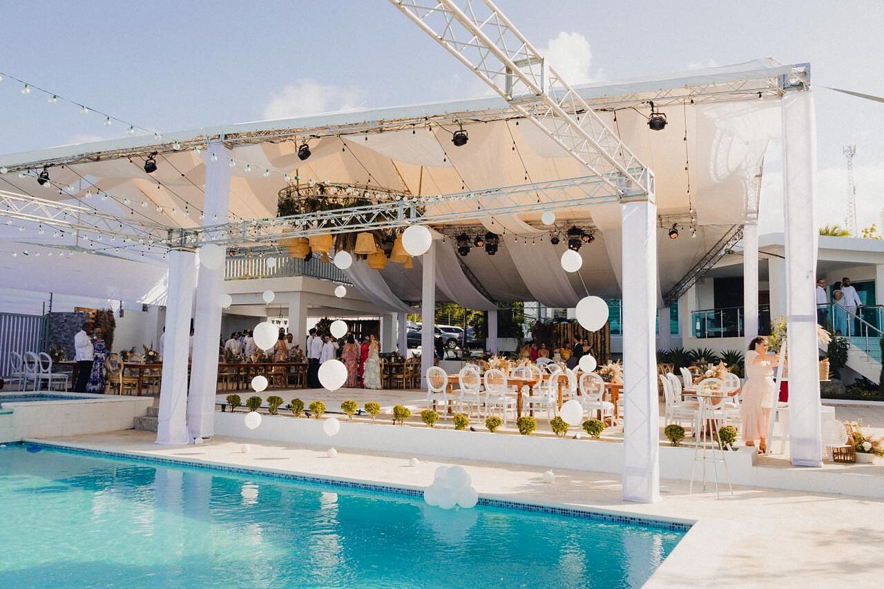 Poolside wedding reception setup with draped tent and string lights